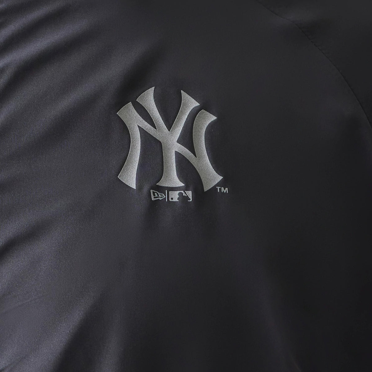 New Era New York Yankees MLB Dark Grey Jacket, front view highlighting a large raised New York Yankees logo in grey on the chest, set against the dark grey fabric with stitching details.
