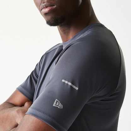 New Era New York Yankees MLB Dark Grey T-Shirt, three-quarter view showing the dark grey short sleeve with a white printed New Era logo near the cuff and a reflective stripe detail near the shoulder, worn by a model.