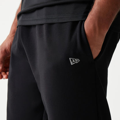 New Era New York Yankees MLB Black Joggers, side view with a model showing the grey New Era flag logo on the lower left leg, featuring an elasticated waistband and side pockets in a soft fabric finish.