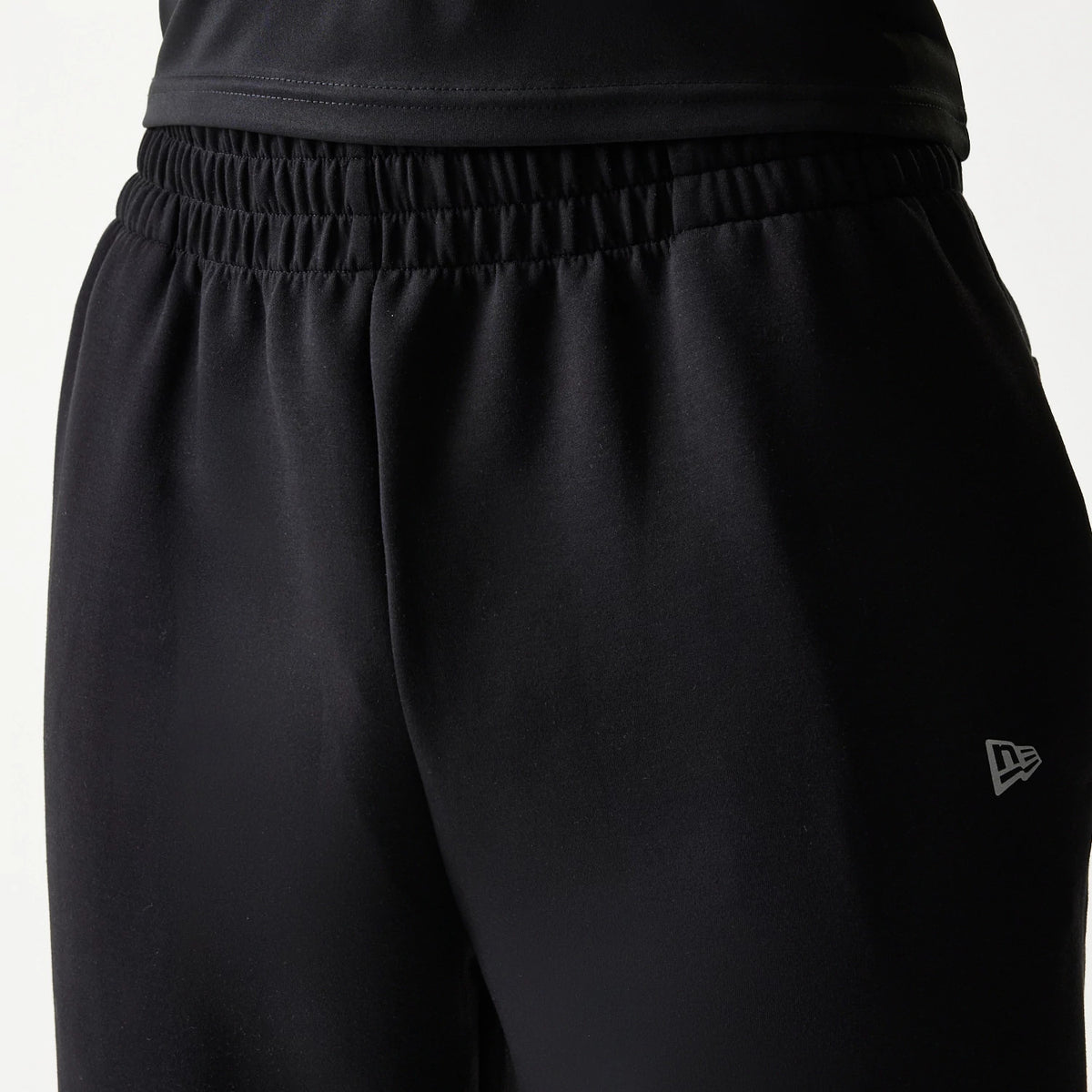New Era New York Yankees MLB Black Joggers, close-up showing the elastic waistband and the New Era flag logo embroidered in white on the upper left thigh, highlighting the black fabric.