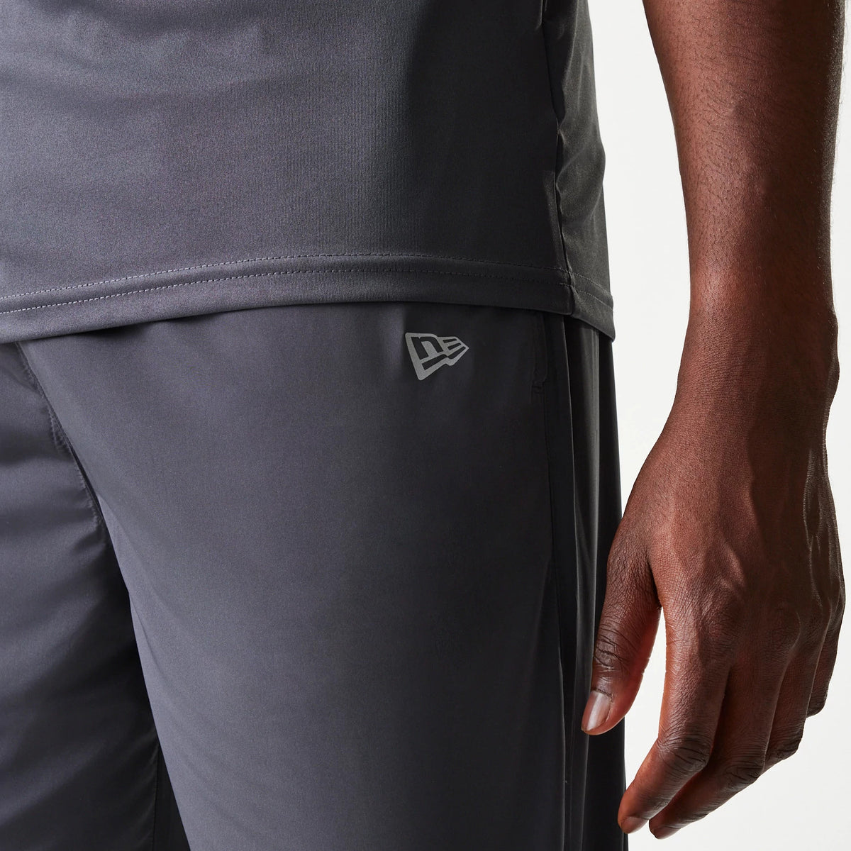 New Era New York Yankees MLB Dark Grey Track Pants, close-up view showing the New Era flag logo on the upper right leg, paired with a matching dark grey track top at the bottom edge.