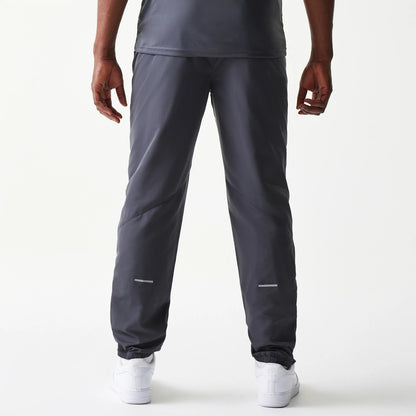 New Era New York Yankees MLB Dark Grey Track Pants, rear view showing a straight-leg cut with elasticated cuffs and reflective near the ankles, styled over white trainers on a model.