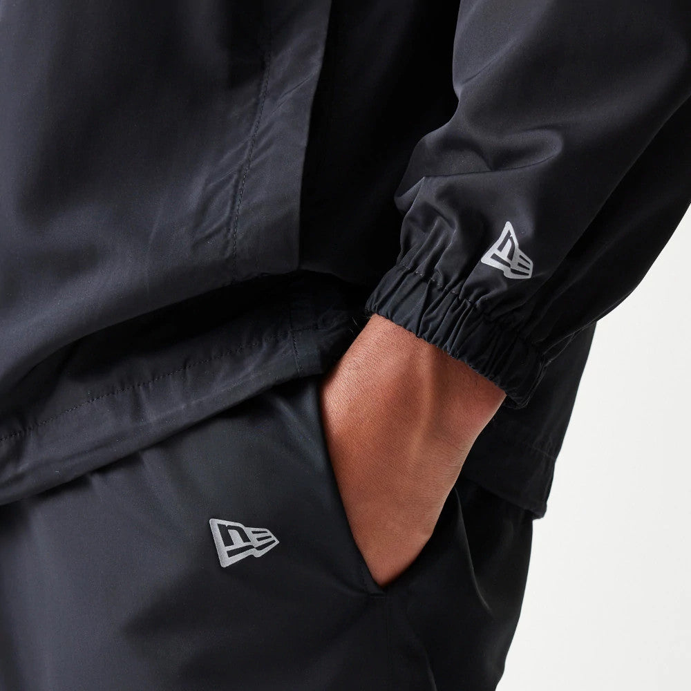 New Era New York Yankees MLB Reflective Logo Black Track Pants, close-up showing the reflective New Era flag logo on the side of the pants and a hand in the pocket, complemented by a matching jacket with an elasticated cuff and logo.