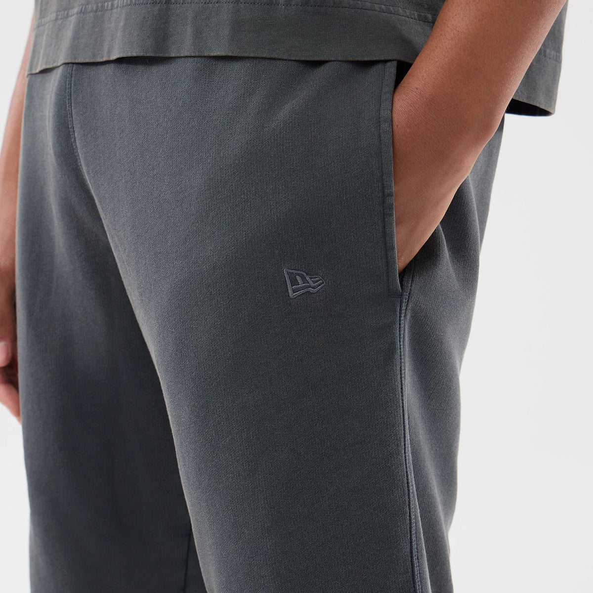 New Era LA Dodgers MLB Washed Dark Grey Shorts, close-up side view showing the dark grey fabric with a embroidered New Era logo near the pocket on the left side, model with hand in pocket showcasing the relaxed fit.