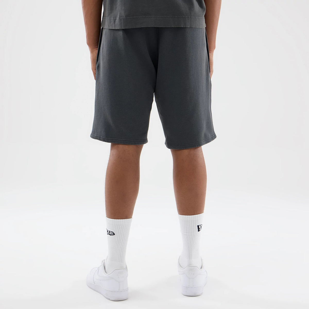 New Era LA Dodgers MLB Washed Dark Grey Shorts, back view showing the clean hemline falling just above the knee and tailoring along the back, styled casually on a model with white socks and trainers.