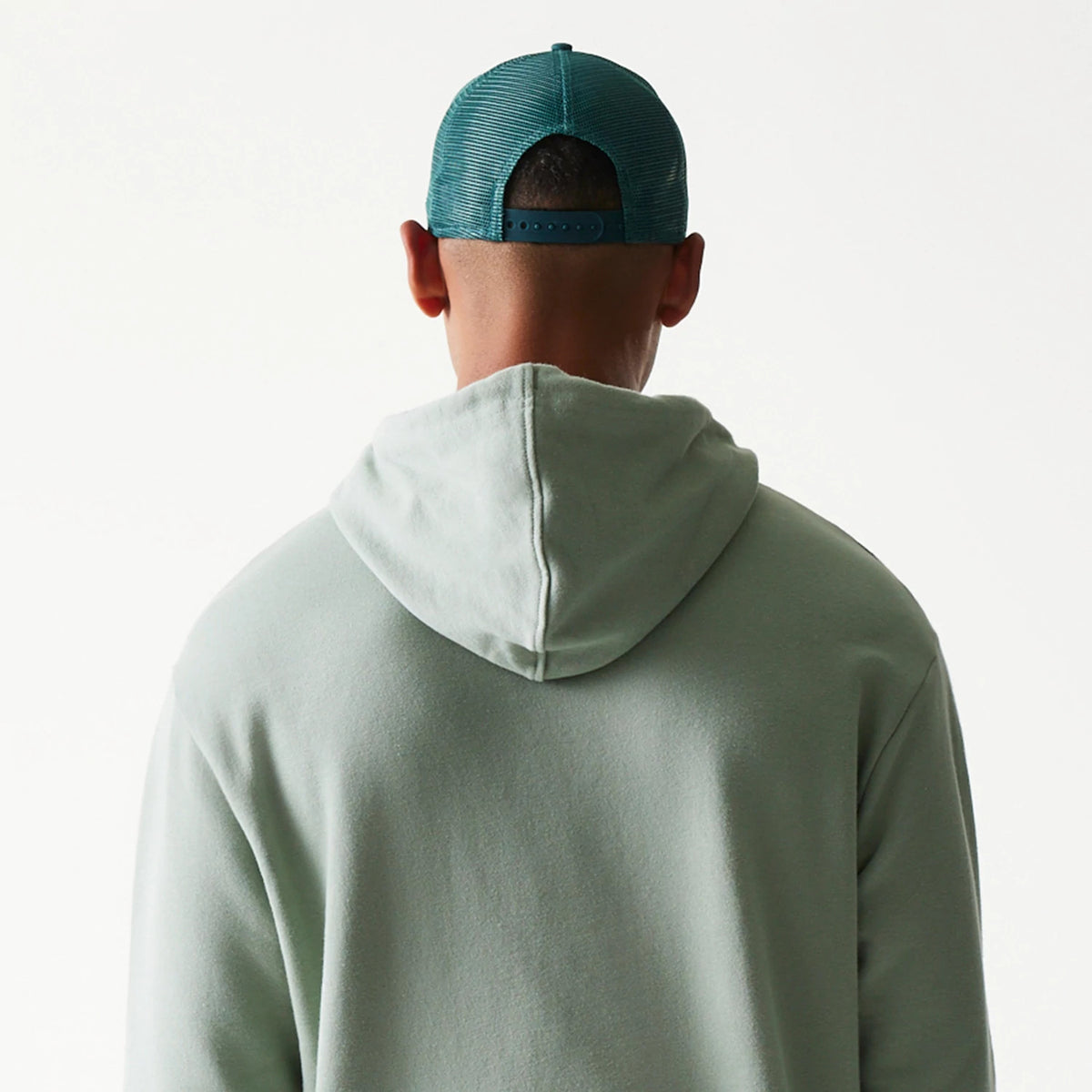 New Era LA Dodgers MLB Midi Green Oversized Pullover Hoodie, back view on-model showing the simple green hood draped over the shoulders, paired with a green cap, highlighting the relaxed oversized fit.