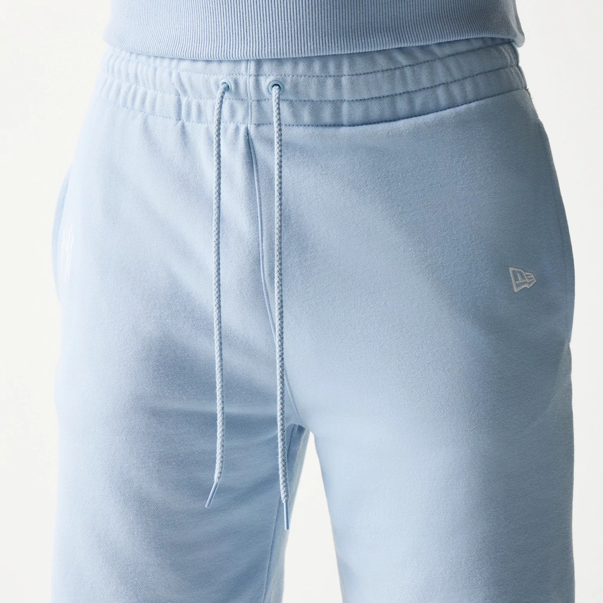 New Era New York Yankees MLB League Essential Midi Blue Shorts, front view showing a drawstring waist, the embroidered New Era logo on the right thigh and the NY Yankees logo on the left thigh.