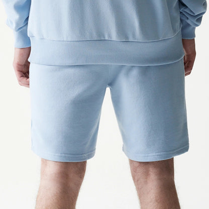 New Era New York Yankees MLB League Essential Midi Blue Shorts, back view on-model showing the light blue fabric extending to above the knee and a matching waistband, paired with a similarly coloured top for a cohesive style.