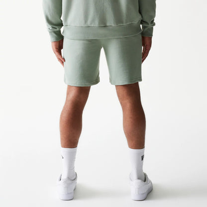 New Era LA Dodgers MLB League Essential Midi Green Shorts, back view on-model showing the soft green fabric reaching just above the knee, paired with matching top and white socks, creating a laid-back, coordinated look.