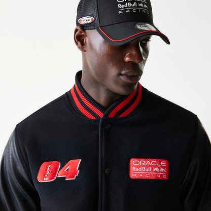 New Era Red Bull Racing Black Varsity Jacket, front view on a model showing red embroidered 04 and Oracle Red Bull Racing patches with a red striped collar, paired with a matching cap displaying the New Era logo on the side.