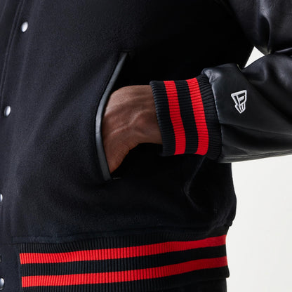 New Era Red Bull Racing Black Varsity Jacket, three-quarter view showing a side pocket with leather trim, a sleeve with embroidered white logo above the red-striped ribbed cuff, and matching waist ribbing.