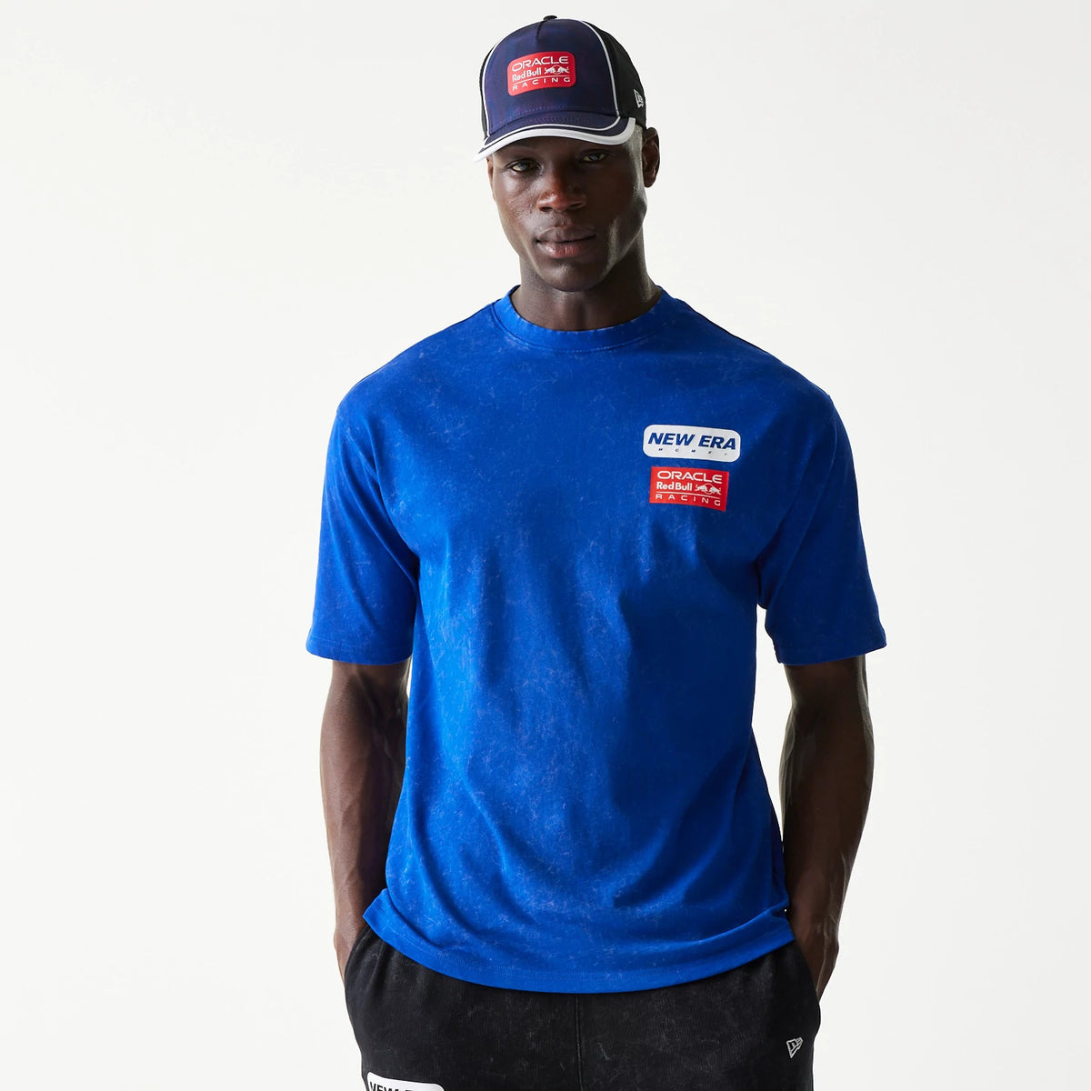 New Era Red Bull Racing Linear Graphic Blue Oversized T-Shirt, front view on-model showcasing a vivid blue colour with a printed New Era and Red Bull Racing logo on the left chest, styled with a matching cap.