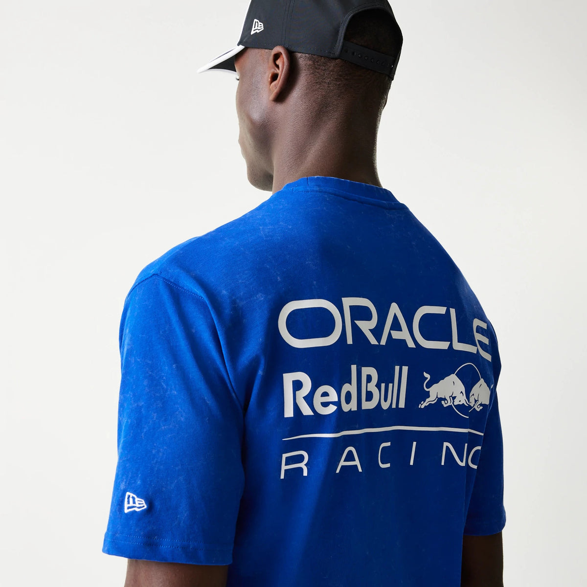 New Era Red Bull Racing Linear Graphic Blue Oversized T-Shirt, back view on model showcasing large white printed Oracle and Red Bull Racing graphics across the upper back, and the New Era embroidered logo on the left sleeve.
