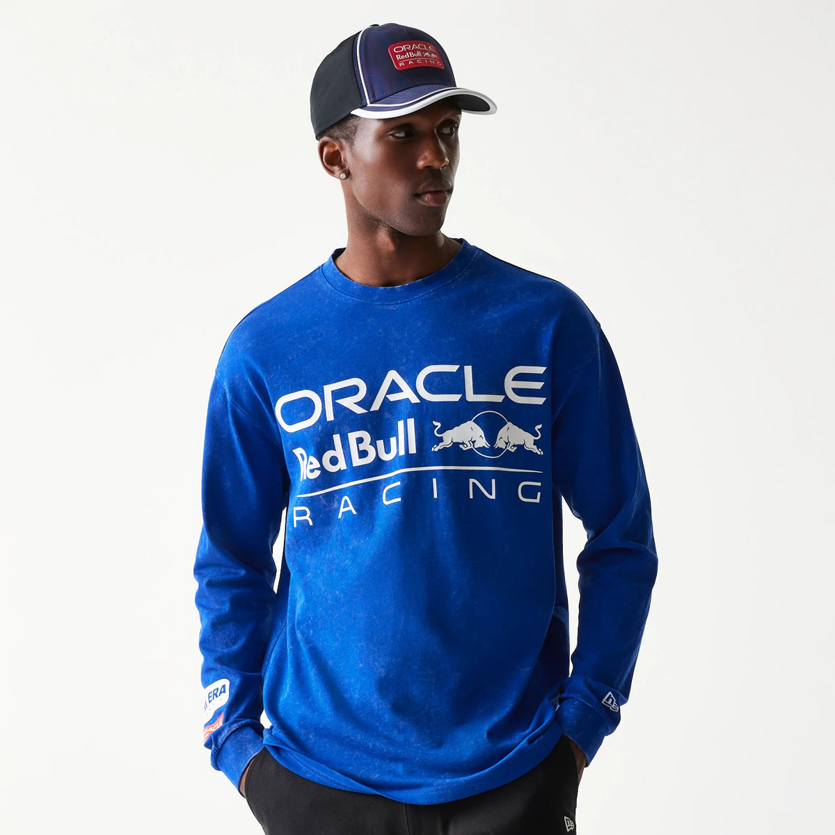 New Era Red Bull Racing Linear Graphic Blue Long Sleeve T-Shirt, front view on-model displaying the white Oracle and Red Bull Racing logo printed across the chest, with New Era branding on the cuff of the left sleeve.