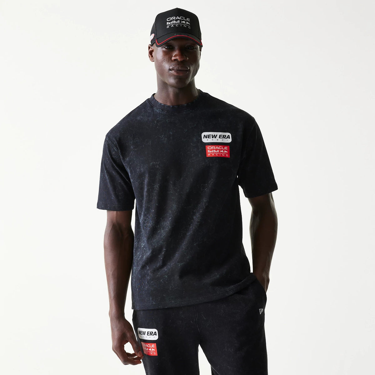 New Era Red Bull Racing Linear Graphic Black Oversized T-Shirt, front view on a model wearing a matching cap and trousers, featuring a New Era embroidered patch and Red Bull Racing logo patch on the chest.