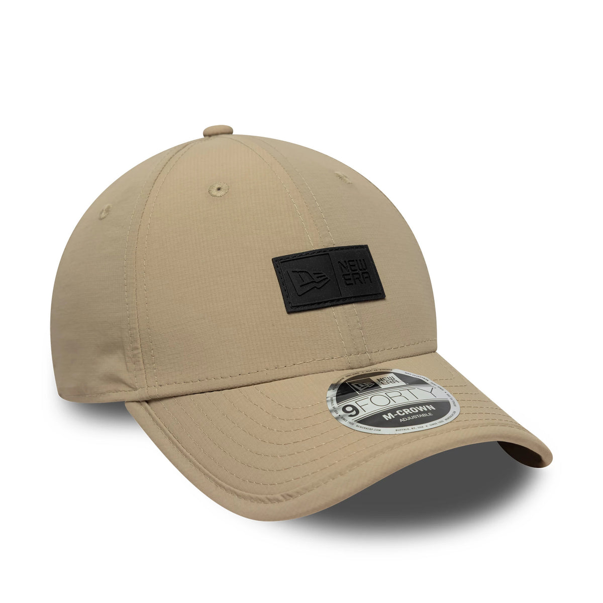 New Era Sport Light Beige 9FORTY M-Crown Cap, three-quarter view showing a black woven New Era patch on the front panel, a curved beige visor with a 9FORTY size sticker, and a matching beige top button and eyelets.