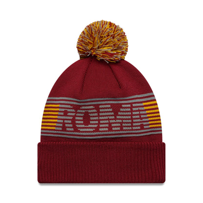 New Era AS Roma Dark Red Bobble Knit Beanie Hat, front view showing the large grey ROMA lettering woven into the crown above a fold-over cuff, with alternating yellow and red stripes and a multicoloured bobble on top.