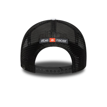 Aprilia Wordmark Black New Era 9FORTY A-Frame Trucker Cap, rear view showing the white and red embroidered #be a racer patch at the centre of the black mesh panels, with a black adjustable snapback closure.