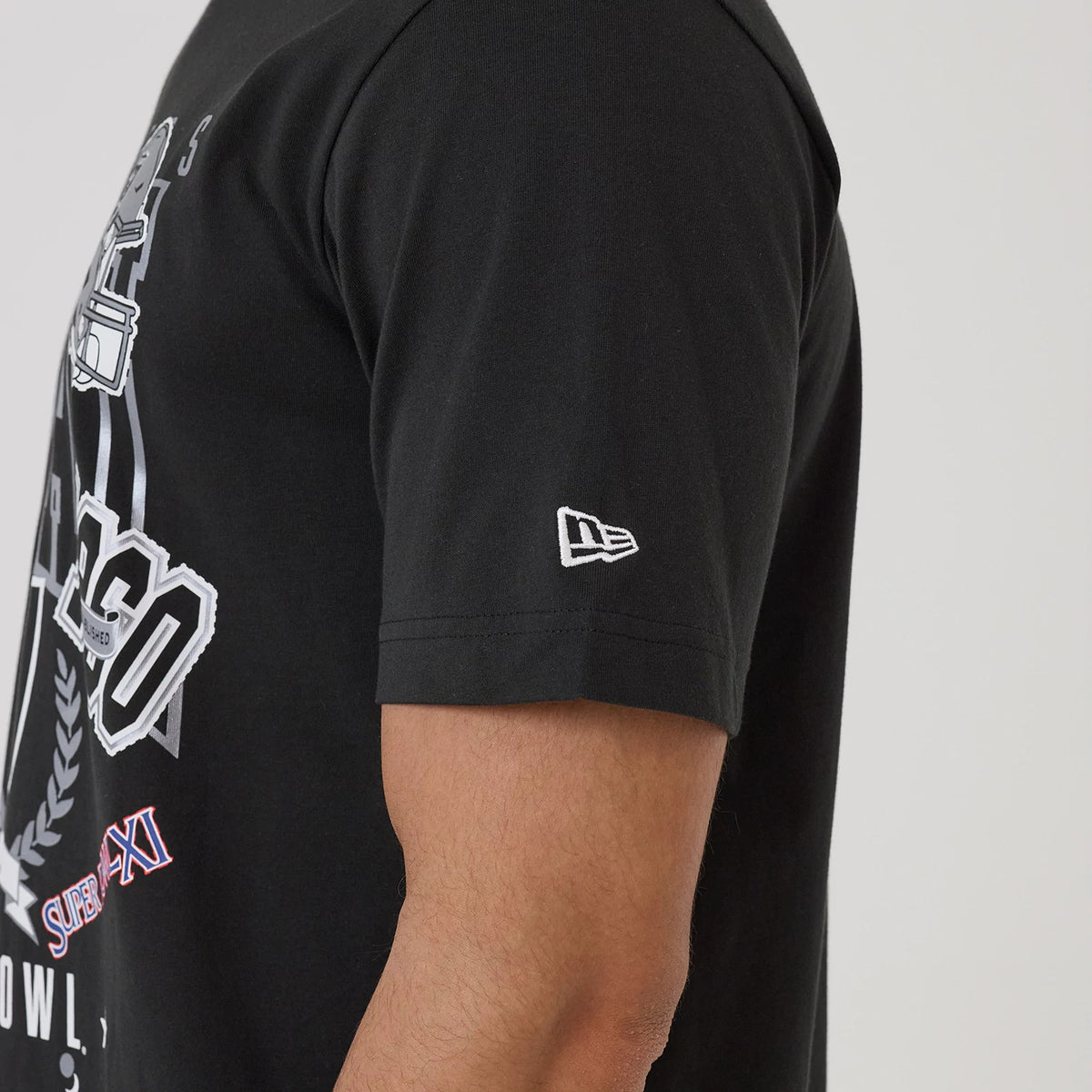 New Era Las Vegas Raiders NFL Sport Classic Black T-Shirt, side view showing the left sleeve with an embroidered New Era logo and a front graphic featuring white lettering and sports-themed imagery.
