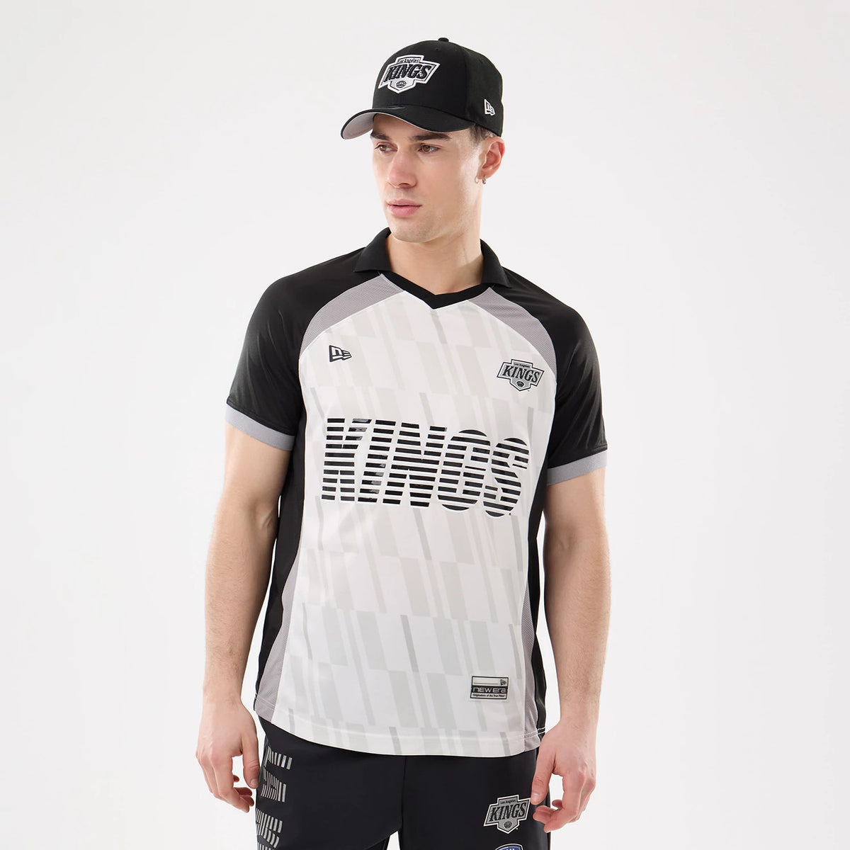 New Era LA Kings NHL Match Black T-Shirt, front view on a model with matching cap, showing the Kings lettering across the chest, a printed Kings logo on the upper right chest and a New Era logo on the left.