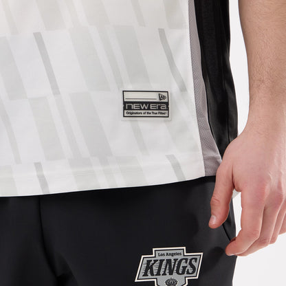 New Era LA Kings NHL Match Black T-Shirt, on-model view showing the lower half of the shirt with a New Era embroidered logo patch near the hem and a grey pattern, paired with trousers featuring the Kings logo.