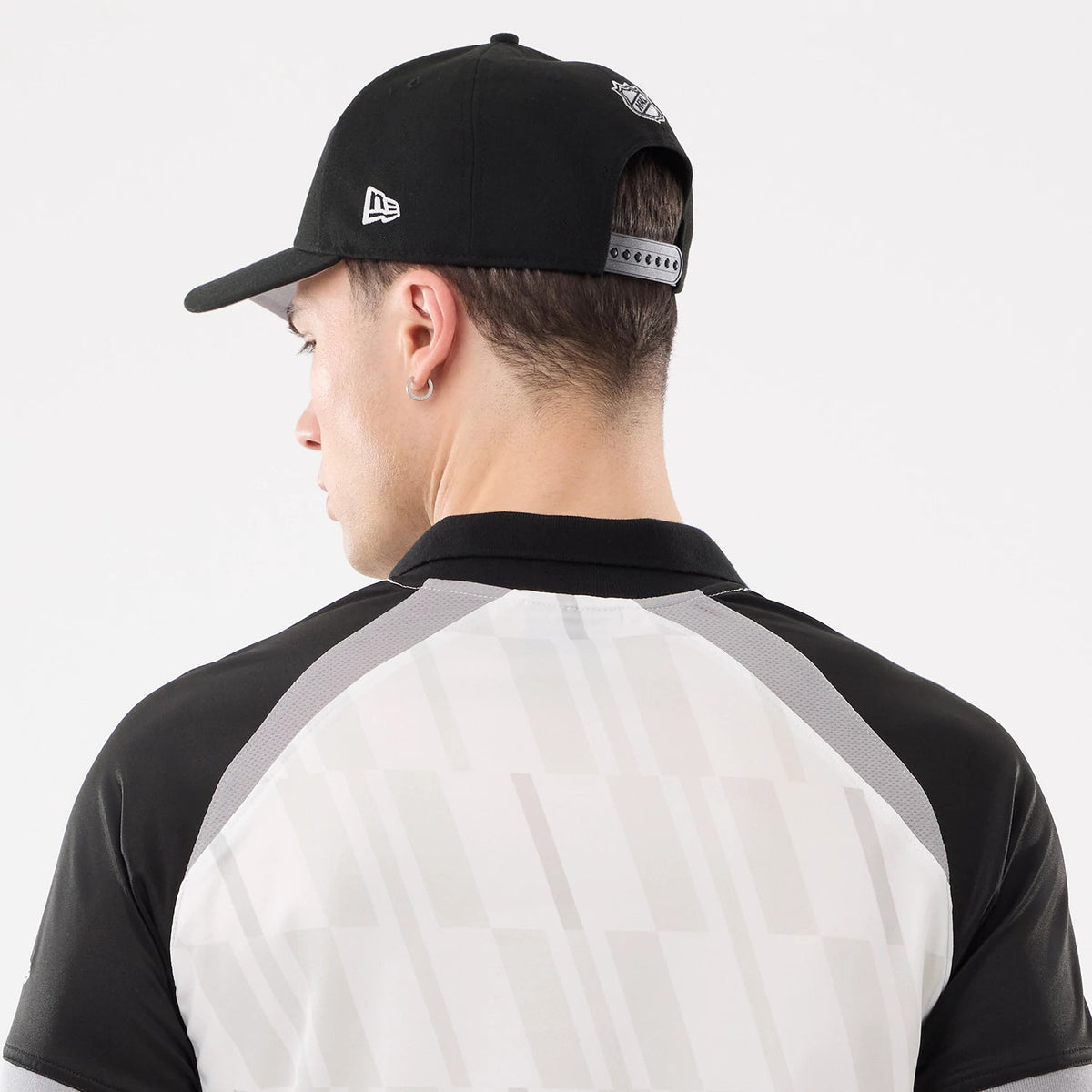 New Era LA Kings NHL Match Black T-Shirt, back view on a model paired with a black cap, highlighting the geometric pattern on the white and grey panels, contrasted with black sleeves and a white embroidered New Era logo on the cap.