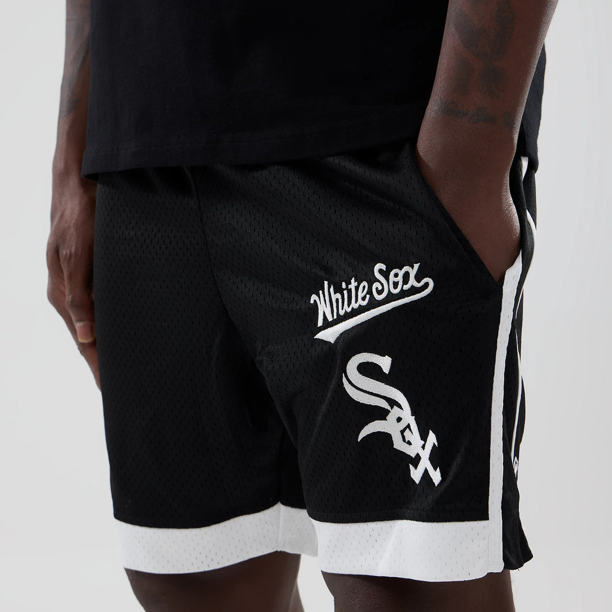 New Era Chicago White Sox MLB Black Mesh Shorts, front view showing a raised White Sox script on the left leg above the large embroidered Sox logo, with contrasting white trim along the hem and sides.