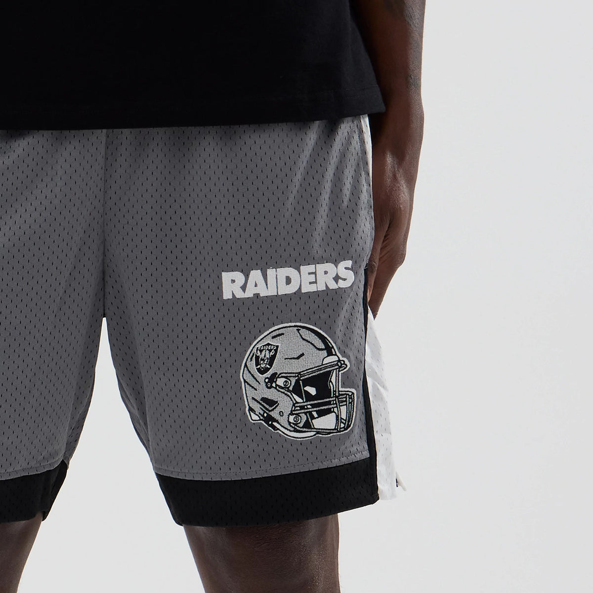 New Era Las Vegas Raiders NFL Grey Mesh Shorts, front view showing the white embroidered Raiders lettering and helmet graphic on the left leg, set against the grey mesh fabric with black trim at the hem.
