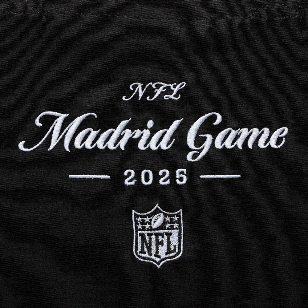 New Era Shield Logo NFL Madrid Game 2025 Black Tote Bag, front view showing embroidered white lettering stating NFL Madrid Game 2025 above an NFL shield logo on the centre of the black fabric.