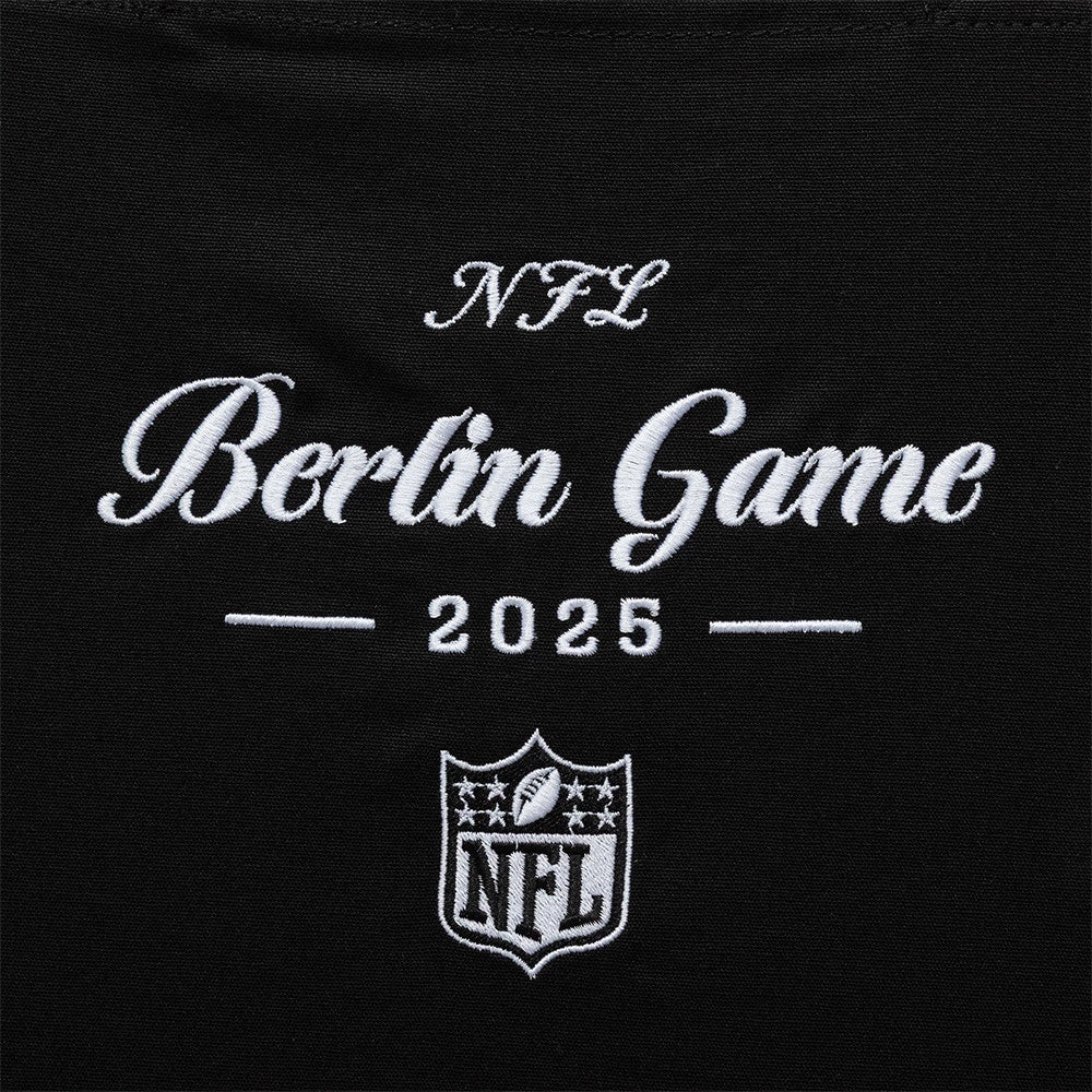 New Era Shield Logo NFL Berlin Game 2025 Black Tote Bag, front view showing white embroidered text NFL Berlin Game 2025 above an embroidered NFL shield logo on the black fabric of the tote.