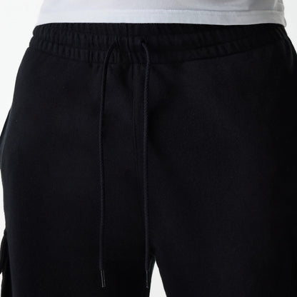 New Era Black Cargo Joggers, front view showing the elasticated waistband with black drawstrings and the upper part of the left leg with pocket seams, featuring a relaxed fit and a plain black design.