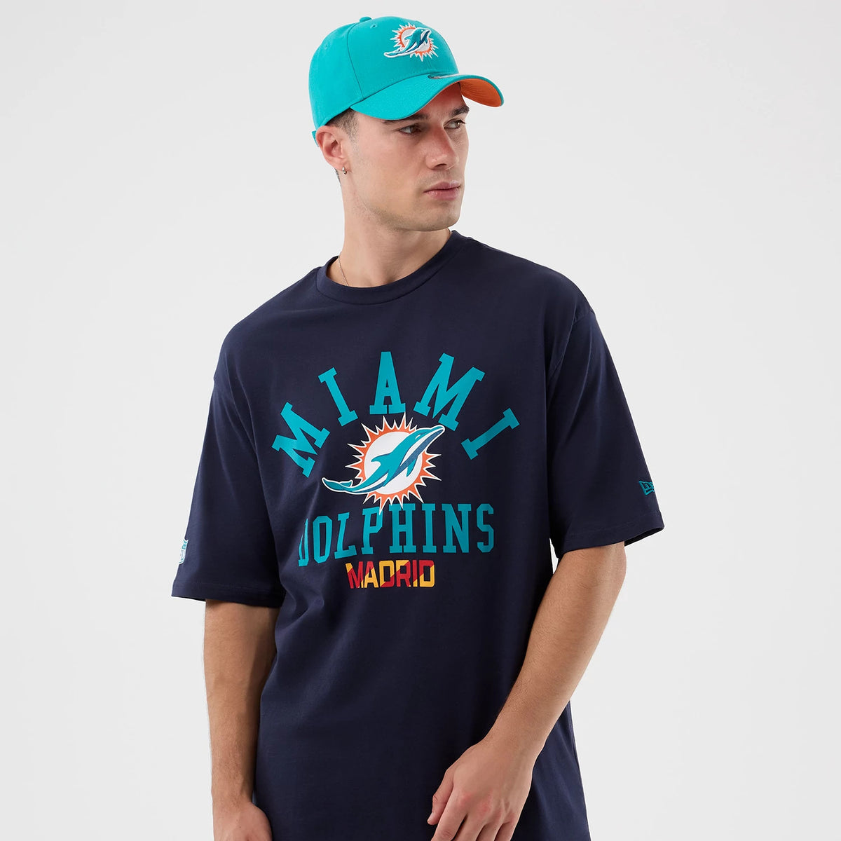New Era Miami Dolphins NFL International Series Games Navy Oversized T-Shirt, front view on-model showing the large Miami Dolphins logo centred on the chest with Miami and Madrid lettering.