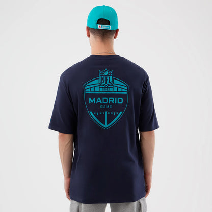 New Era Miami Dolphins NFL International Series Games Navy Oversized T-Shirt, back view on a model in a turquoise cap showing a large teal printed graphic with Madrid Game text and NFL 2023 emblem across the shoulders.