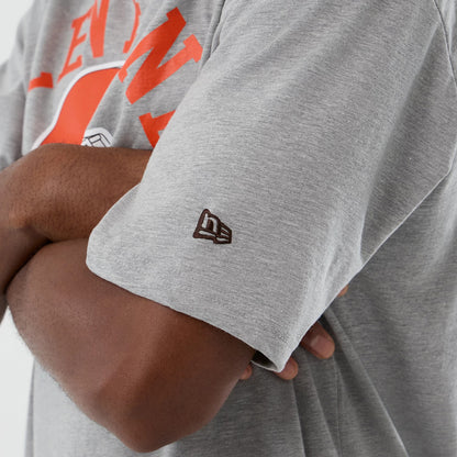 New Era Cleveland Browns NFL International Series Games Grey Oversized T-Shirt, on-model view showing a brown embroidered New Era logo on the left sleeve and a large orange graphic with lettering across the chest.