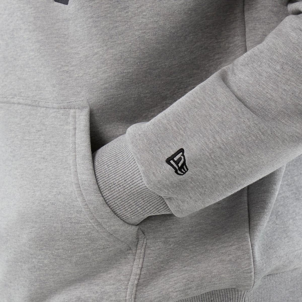 New Era Jacksonville Jaguars NFL International Series Games Grey Pullover Hoodie, three-quarter view focusing on the grey ribbed sleeve cuff with an embroidered New Era logo and a glimpse of the front kangaroo pocket.