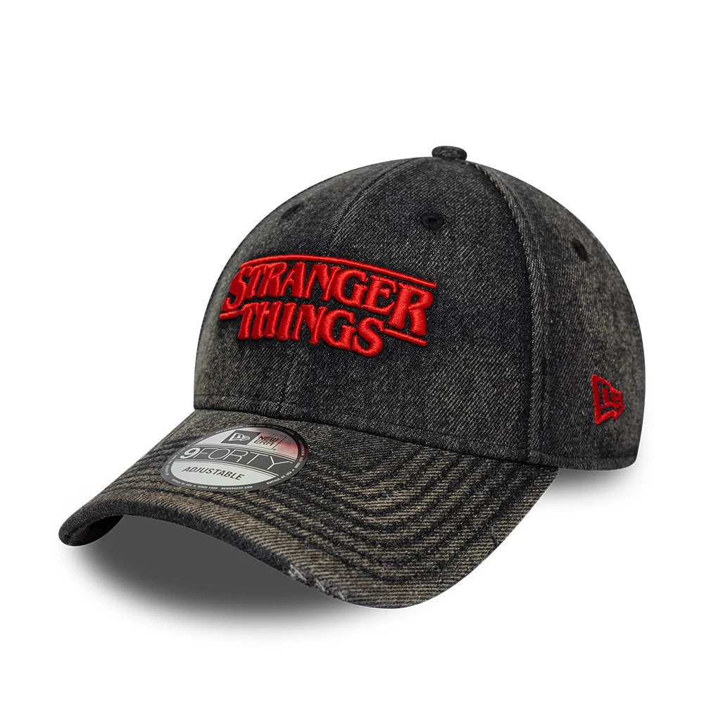 Stranger Things Distressed Black New Era 9FORTY Adjustable Cap, three-quarter view showing red embroidered Stranger Things logo on the front panel, curved visor with 9FORTY size sticker, and red New Era flag logo on the left side.