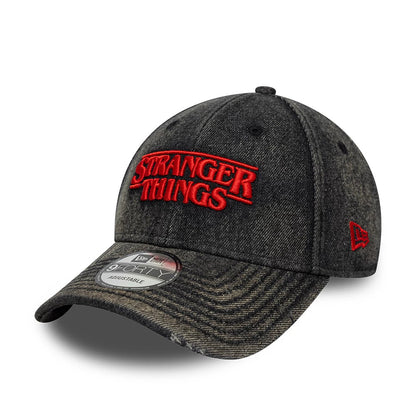 Stranger Things Distressed Black New Era 9FORTY Adjustable Cap, three-quarter view showing red embroidered Stranger Things logo on the front panel, curved visor with 9FORTY size sticker, and red New Era flag logo on the left side.