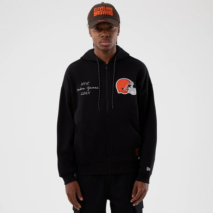 New Era Cleveland Browns NFL International Series Games Black Full Zip Hoodie, front view on a model with a matching cap, displaying the embroidered Cleveland Browns logo on the chest and NFC London Games 2023 lettering on the left side.
