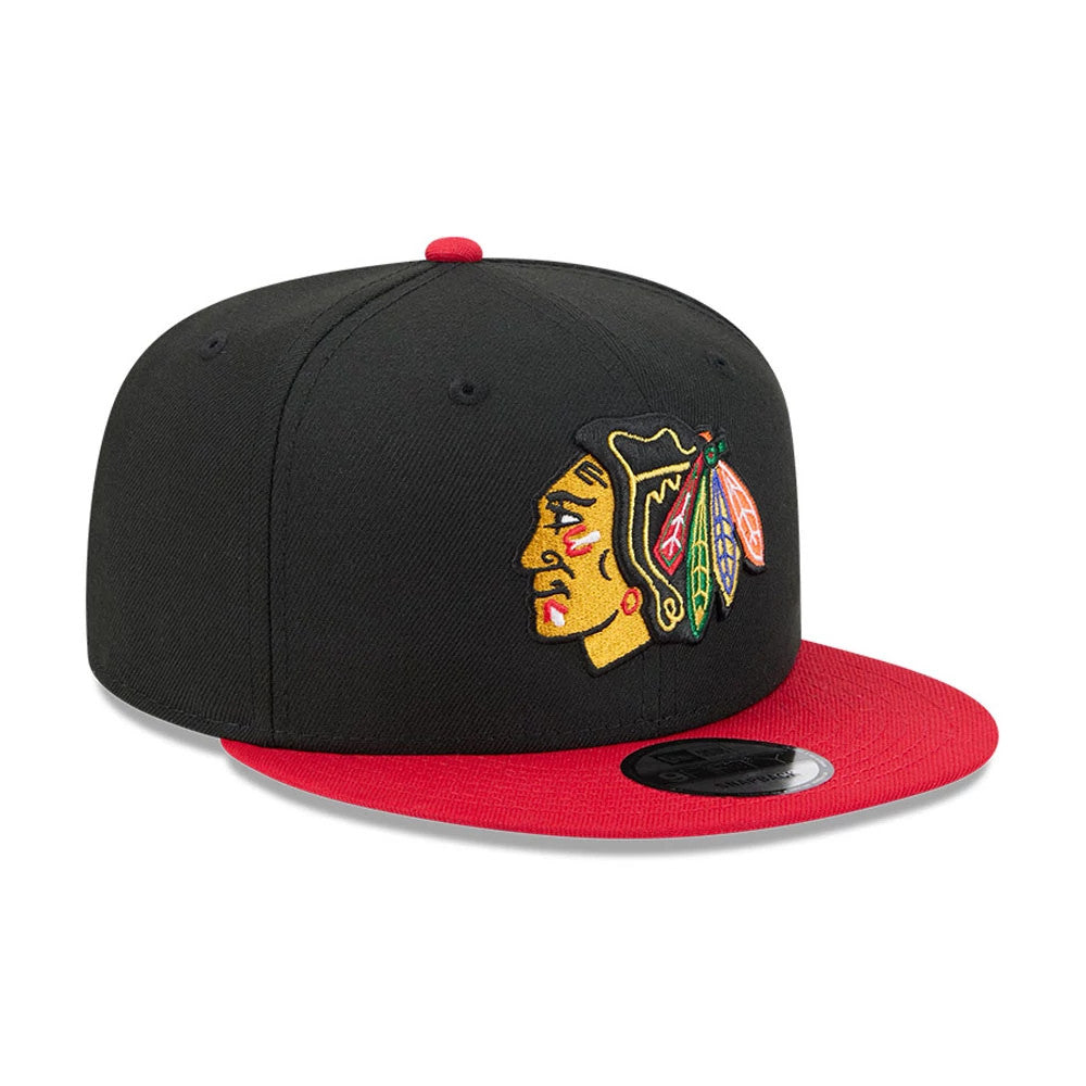Chicago Blackhawks NHL Evergreen Black New Era 9FIFTY Snapback Adjustable Cap, three-quarter view showing the colourful embroidered front logo, red flat visor with a 9FIFTY size sticker, and matching red top button.