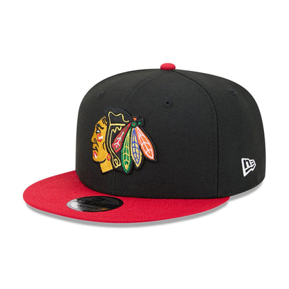 Chicago Blackhawks NHL Evergreen Black New Era 9FIFTY Snapback Adjustable Cap, three-quarter view showing a raised embroidered team logo in multi-colour on the front black panel, featuring a red visor with a 9FIFTY size sticker.