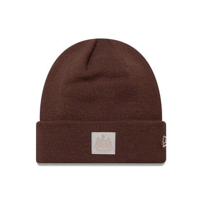 New Era Newcastle United FC Patch Brown Cuff knit Beanie Hat, front view showing the team crest patch on the cuff and New Era flag logo on the left side, all in a rich brown knit fabric.