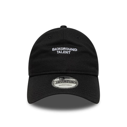 New Era Slogan Background Talent Black 9TWENTY Adjustable Cap, front view showing white embroidered BACKGROUND TALENT text on the centre of the black crown and a 9TWENTY size sticker on the curved black visor.