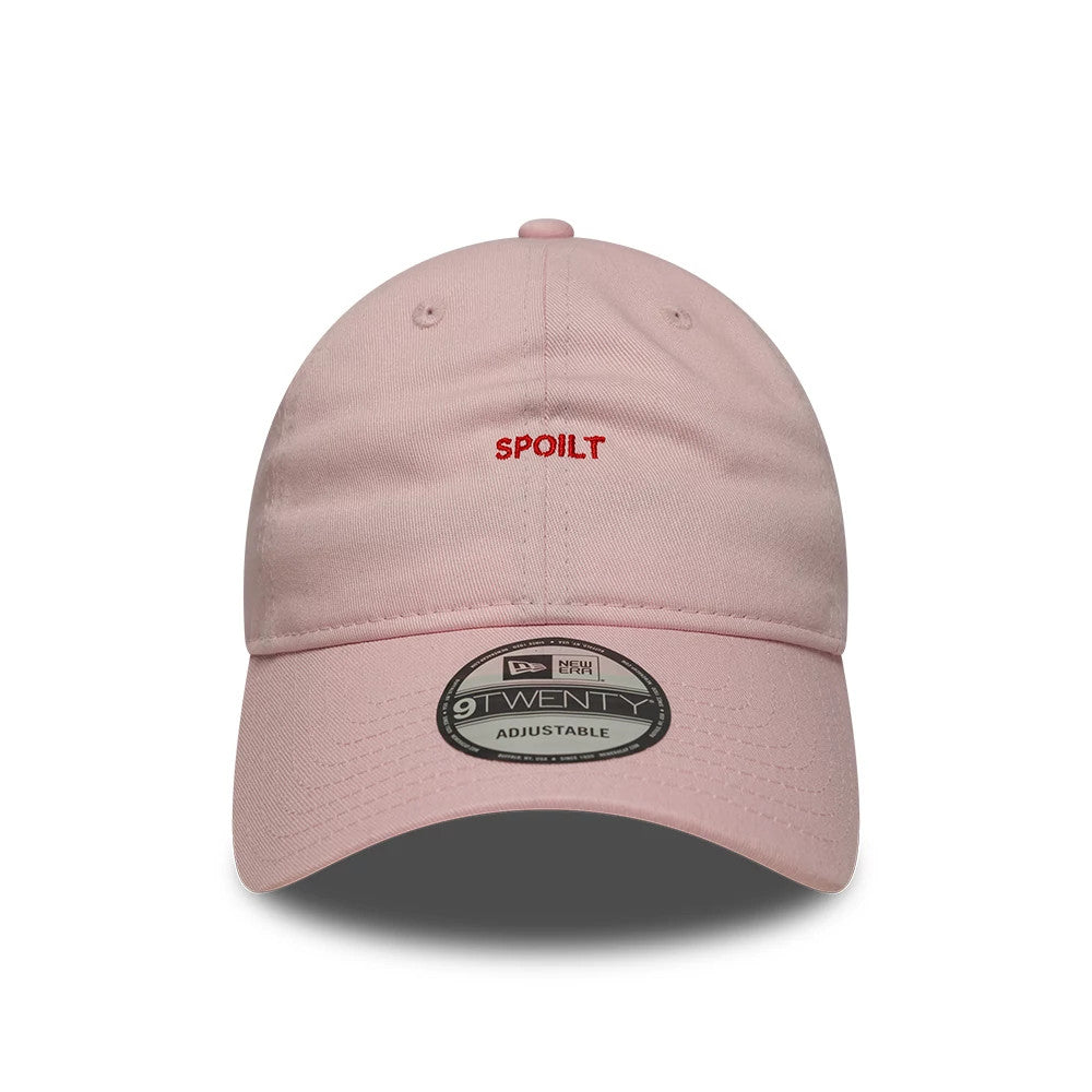 New Era Slogan Spoilt Pastel Pink 9TWENTY Adjustable Cap, front view showing the red embroidered Spoilt text on the unstructured pastel pink crown, curved visor with 9TWENTY size sticker, and top button.