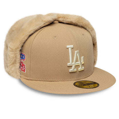 LA Dodgers MLB World Series Light Beige New Era 59FIFTY Fitted Cap, three-quarter view showing the cream embroidered LA logo prominently on the front panel, beige fur-lined ear flaps, and a gold 59FIFTY size sticker on the visor.