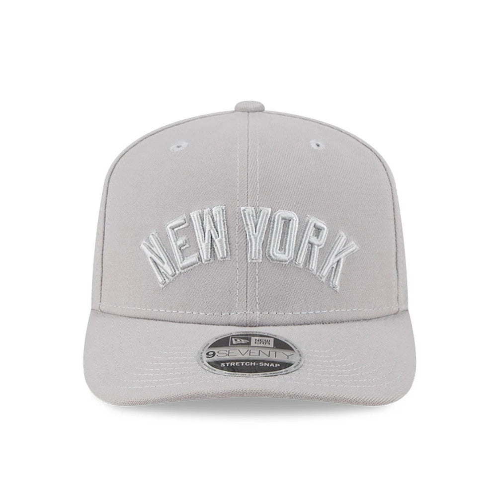 New York Yankees MLB Script Grey New Era 9SEVENTY Stretch Snap Adjustable Cap, front view showing raised white embroidered New York lettering on the light grey crown with a curved visor and a 9SEVENTY size sticker.