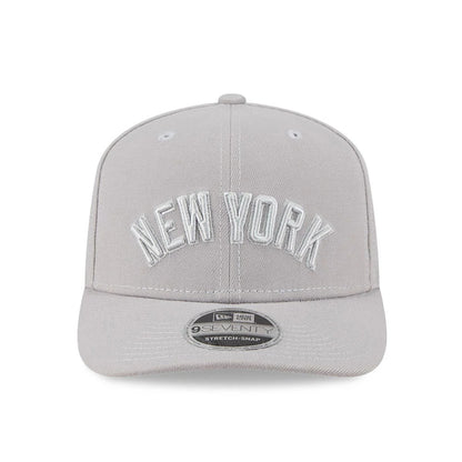 New York Yankees MLB Script Grey New Era 9SEVENTY Stretch Snap Adjustable Cap, front view showing raised white embroidered New York lettering on the light grey crown with a curved visor and a 9SEVENTY size sticker.
