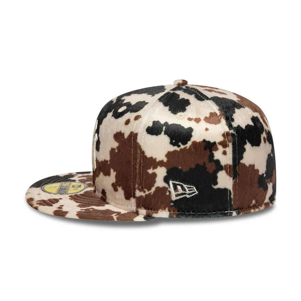 New York Yankees Animal Print Cow Beige New Era 59FIFTY Fitted Cap, side view showing the white New Era flag logo on the multicoloured cow-print crown and a gold 59FIFTY size sticker on the flat visor.