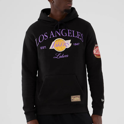 New Era LA Lakers NBA Hardwood Classic Black Pullover Hoodie, front view on-model showing the purple Los Angeles Lakers graphic across the chest, a Western Conference patch on the left sleeve, and a New Era logo embroidered near the cuff.