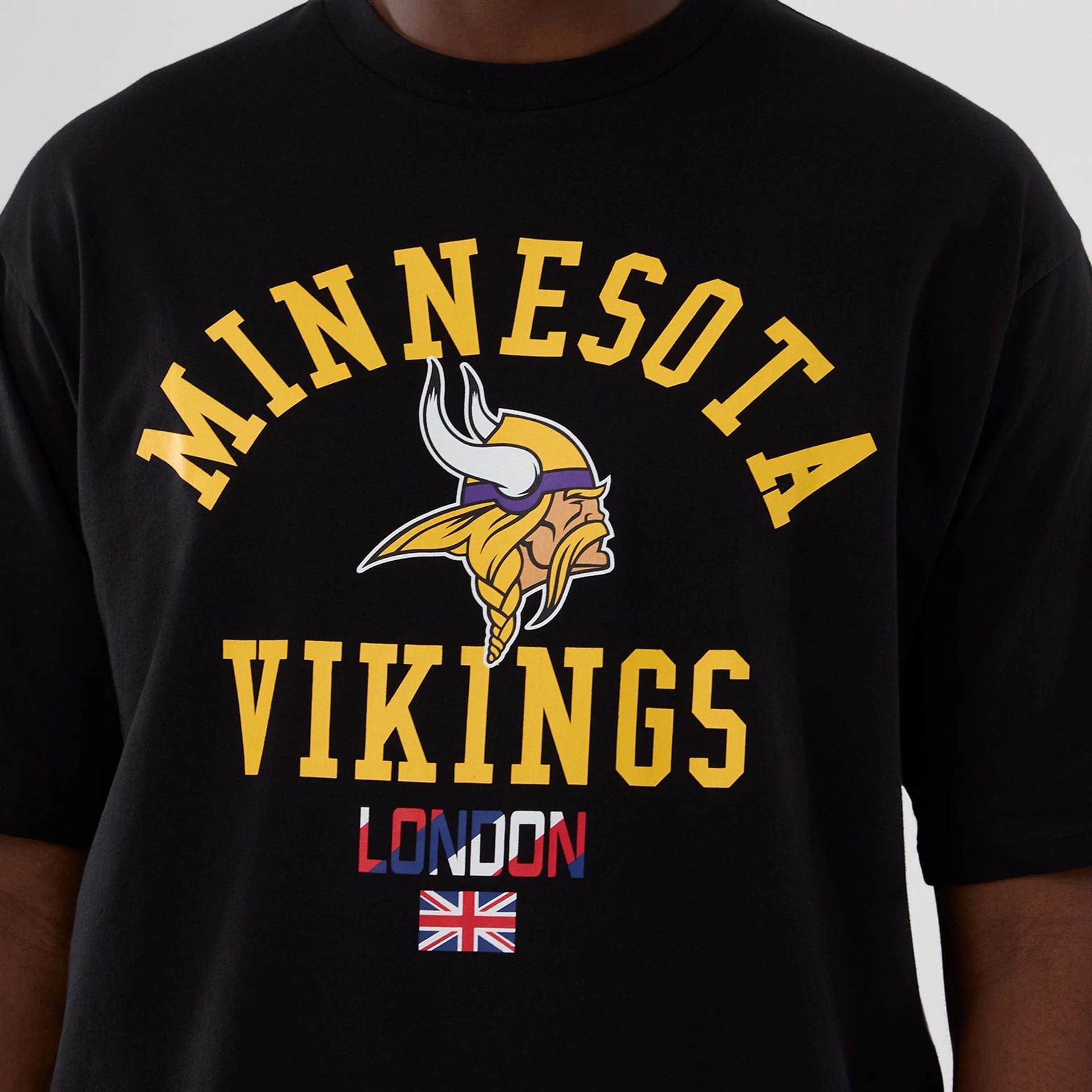 The Male model is wearing Minnesota Vikings NFL International Series Games 2025 Black Oversized T-Shirt  3
