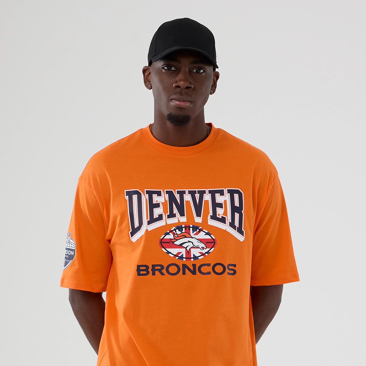 The Male model is wearing Denver Broncos NFL International Series Games 2025 Orange Oversized T-Shirt 3
